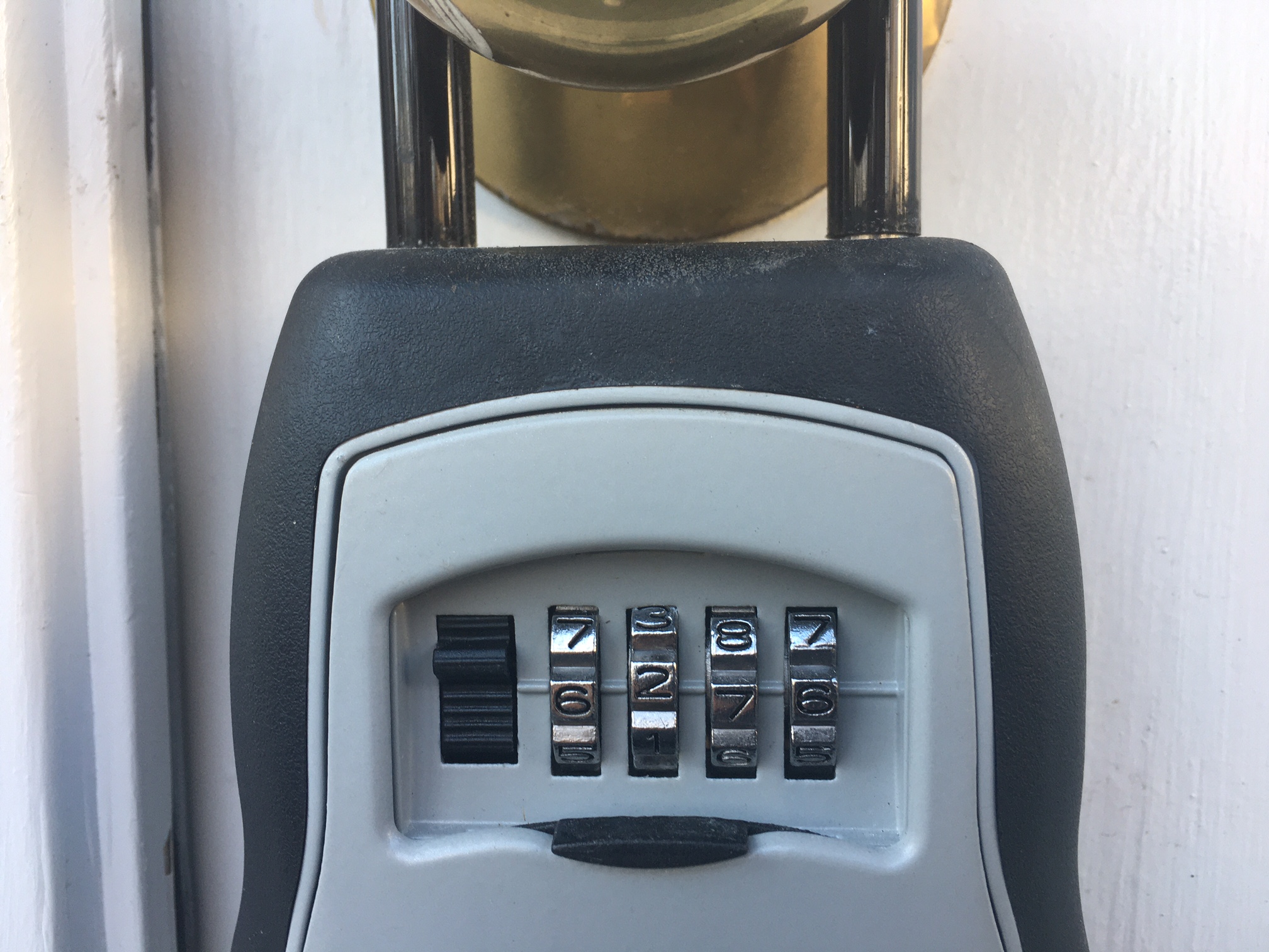 A combination Masterlock hanging on a doorknob.